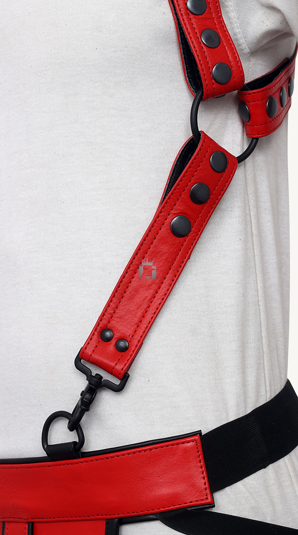 Side angle view of a man wearing a red Genuine Leather Bondage Harness with Adjustable Strap and jockstrap on a light yellow background