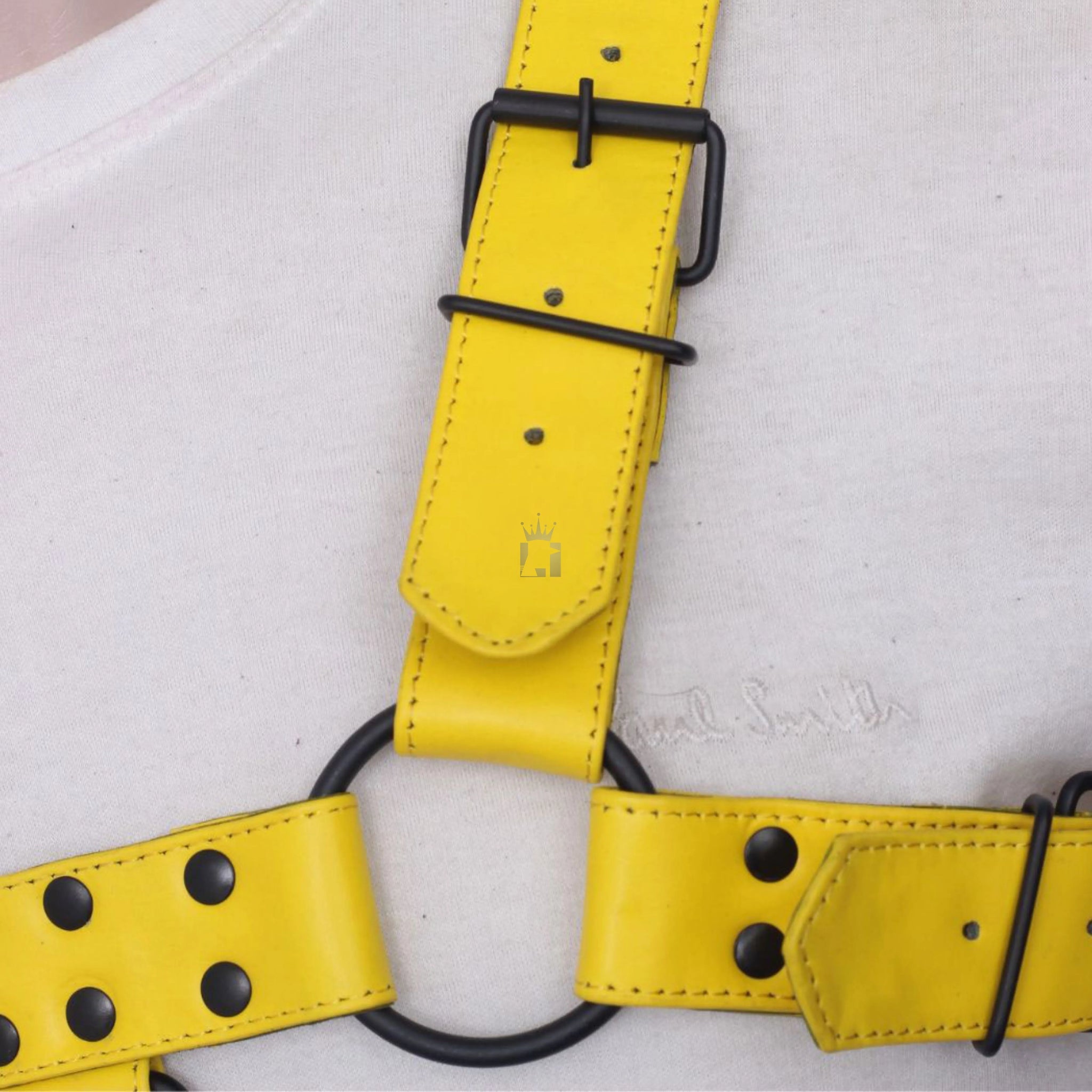 side angle view of a black leather o-ring with buckles and nickel-plated reverts on it on a white background
