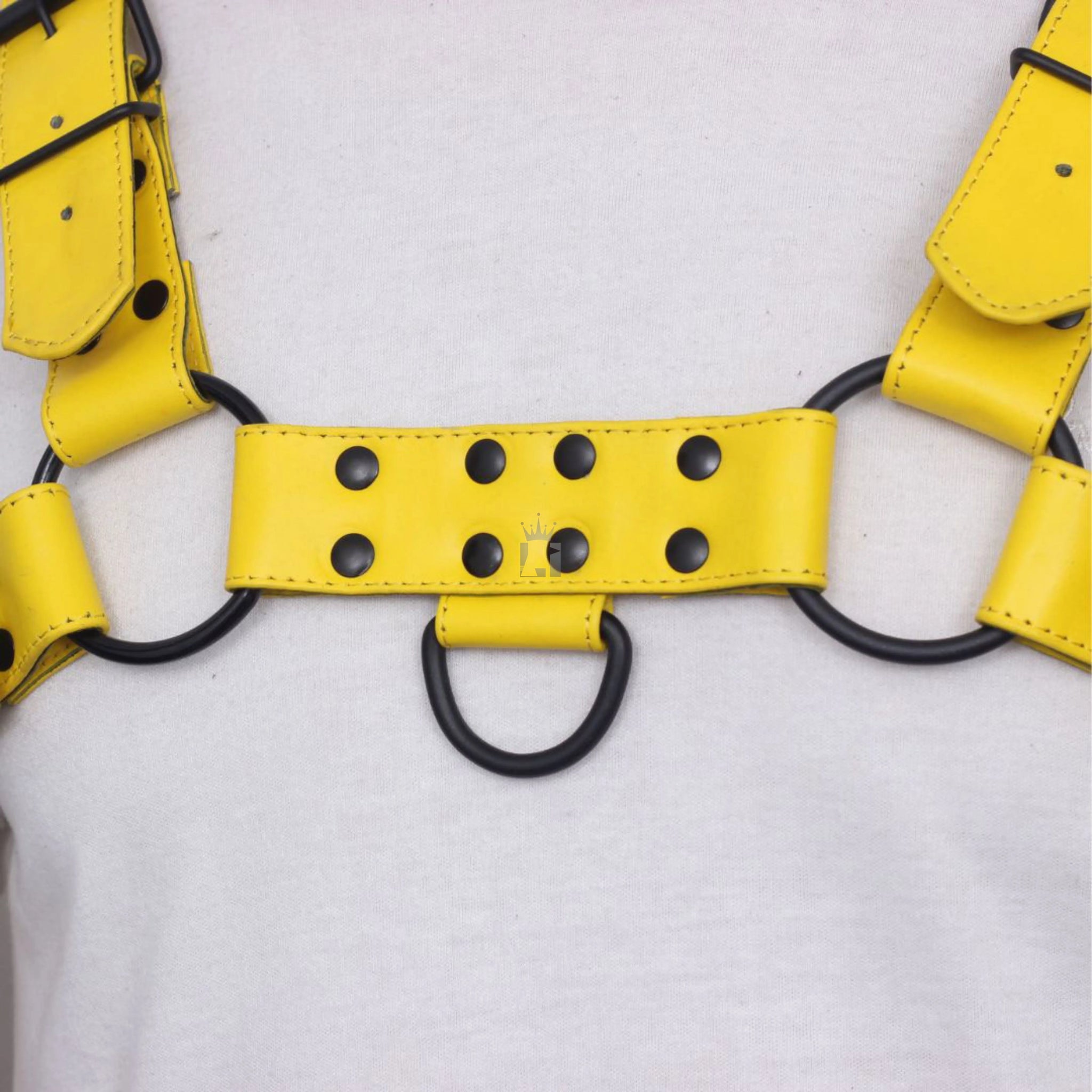 
front angle view of  a dummy in a white shirt wearing a black leather chest bondage harness with adjustable buckles, rivets, steel bonded o-rings in infographic style on a white background