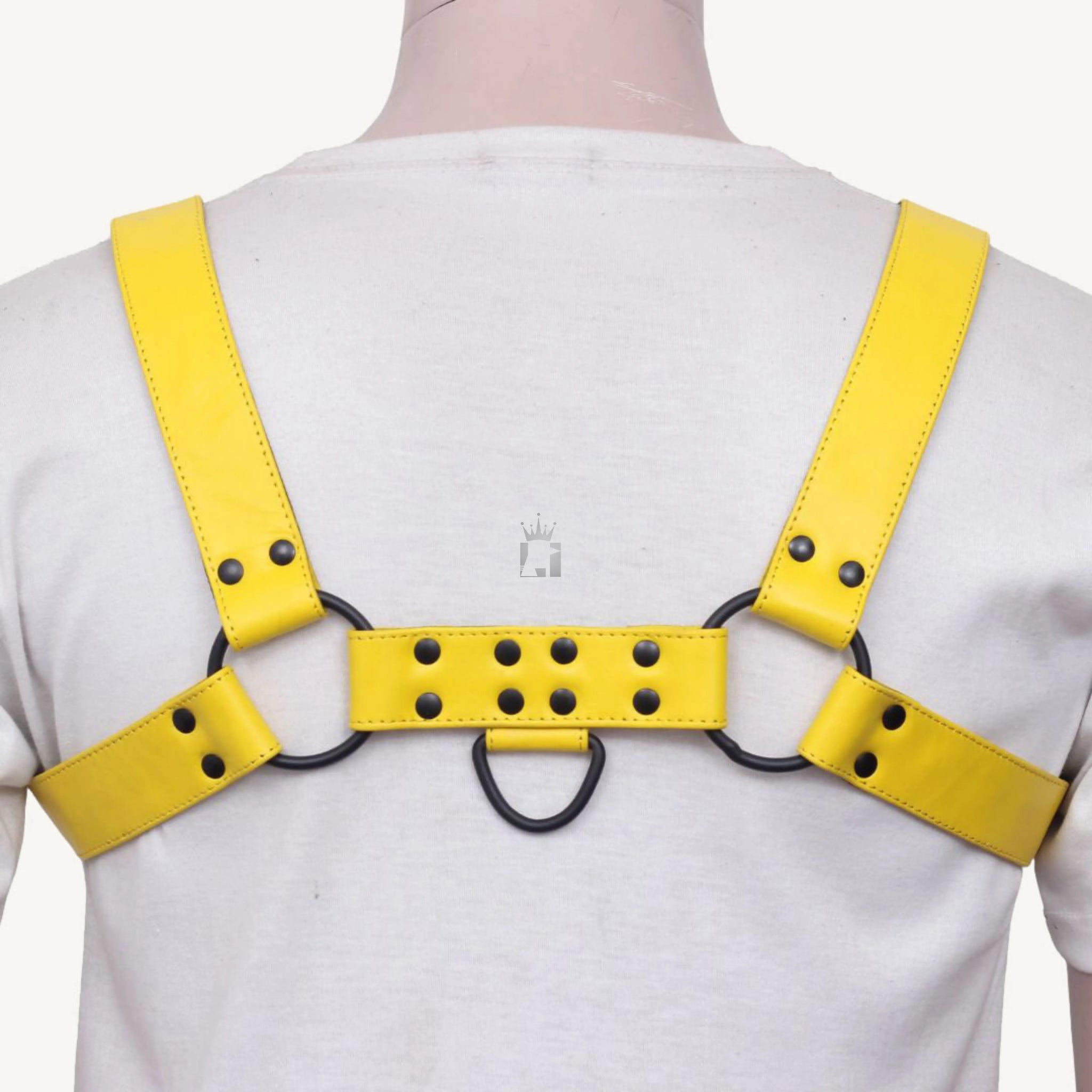 
back-side angle view of a dummy wearing a white shirt with a black leather chest bondage harness with nickel-plated reverts on it on a white background