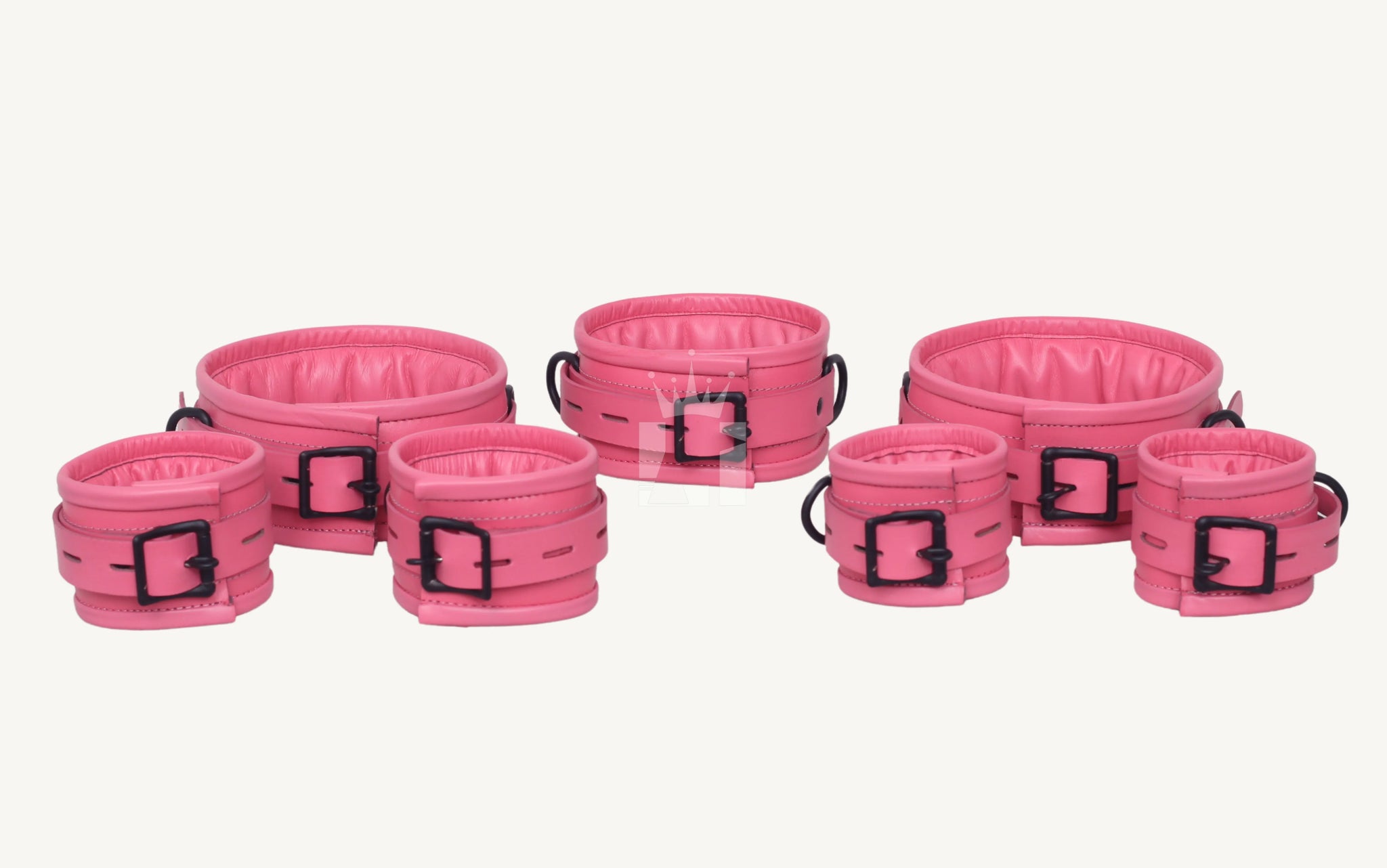 Close-up angled view of pink leather cuffs, 7 pcs set featuring padded interiors, black metal buckles, and D-rings, designed for comfortable wrist restraint in BDSM play.