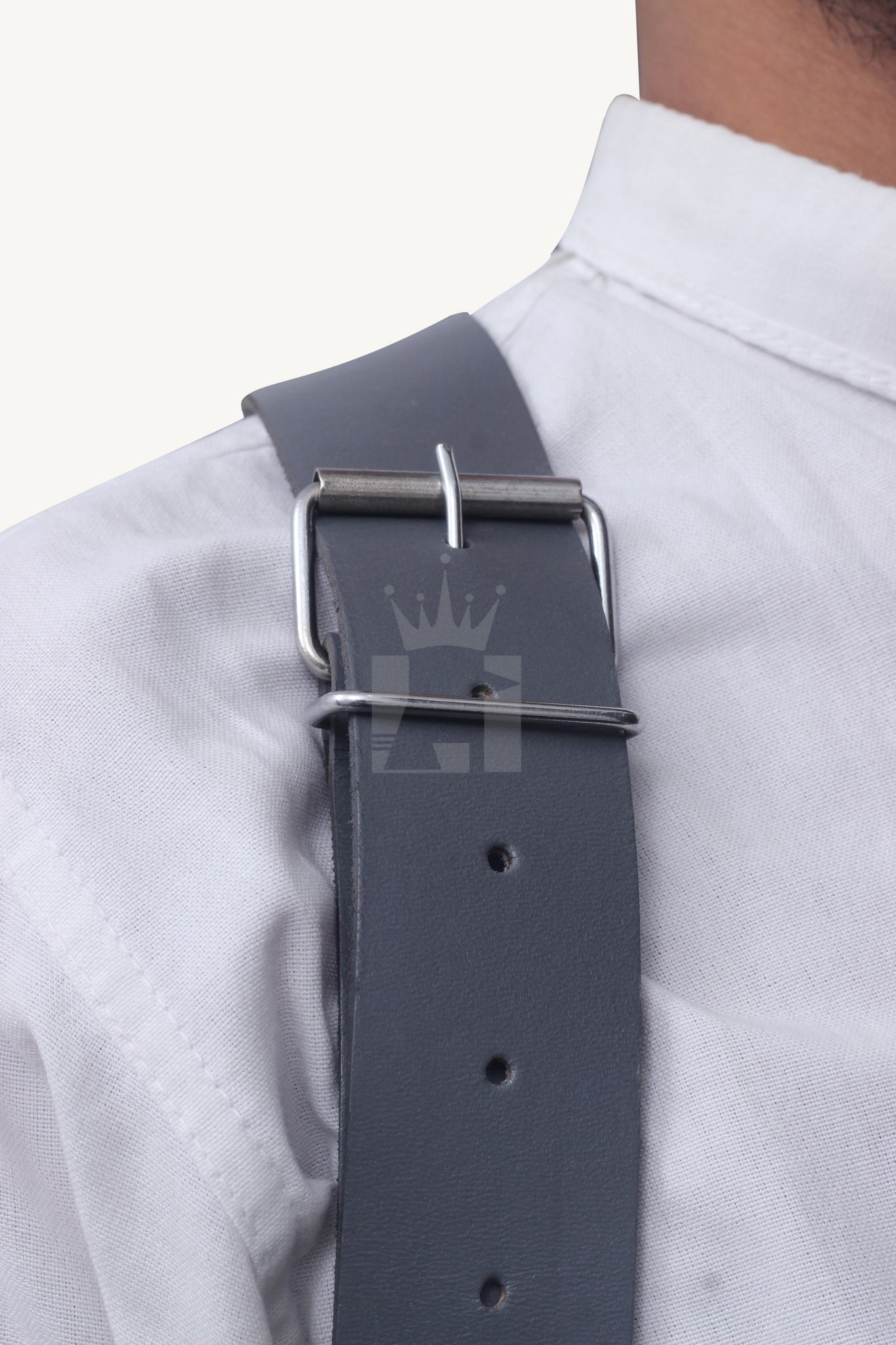 Detailed view of silver buckle fastening on leather shoulder strap.