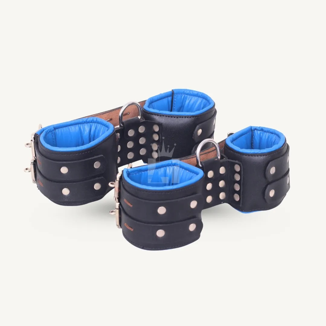 Angled view of black padded leather suspension cuffs with blue interior lining and strong riveted D-ring attachments.
