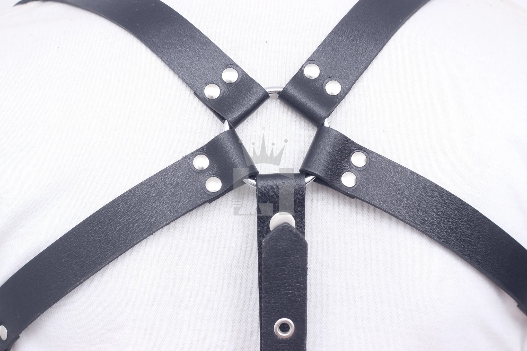 Close-up of black leather straps crossing at the back with silver O-ring connection.