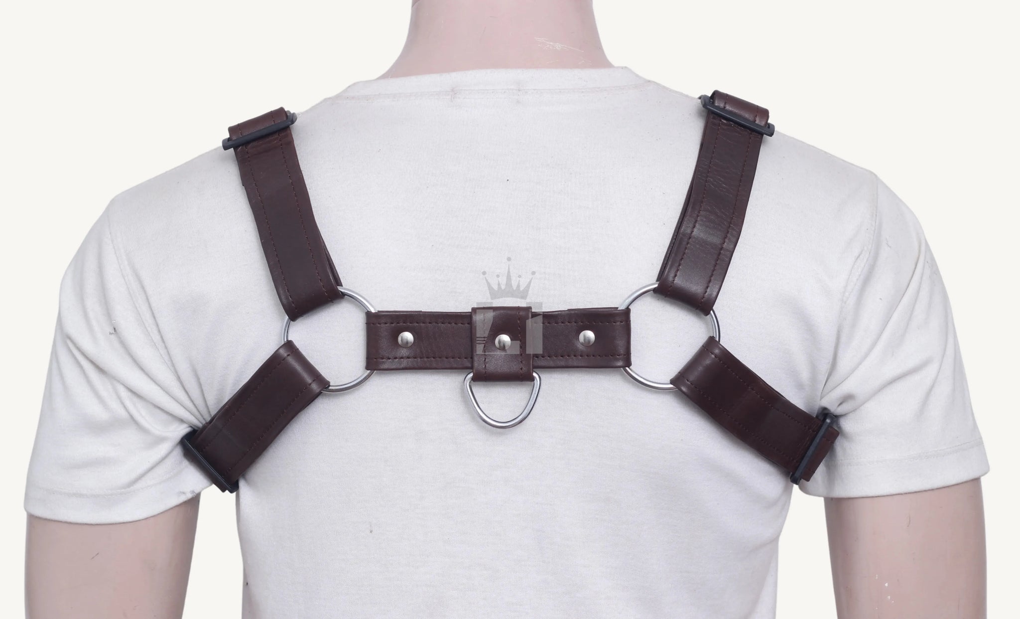 Back view of brown leather harness featuring silver O-rings, rivets, and adjustable strap design.