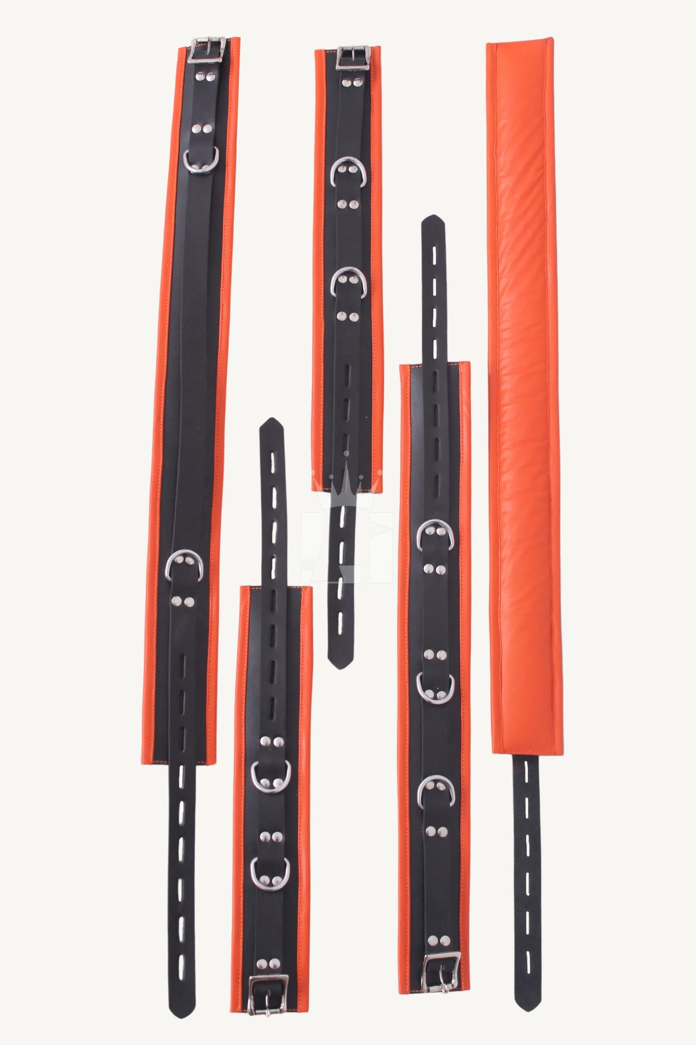 Overhead flat lay view of multiple black and orange leather Bondage cuffs with buckles and D-rings