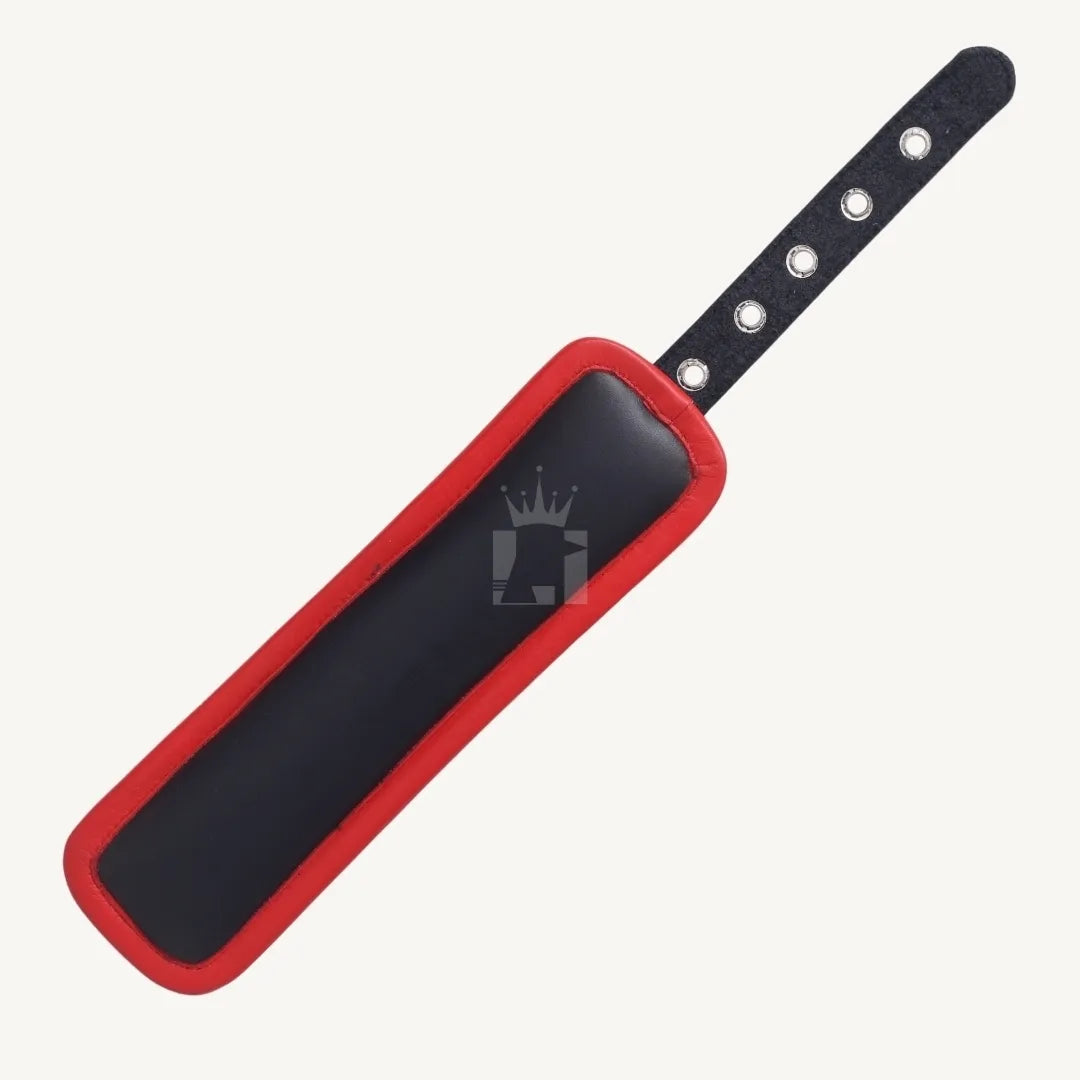 Overhead flat lay back view of a black and red leather handcuffs showing padded surface and multiple eyelets