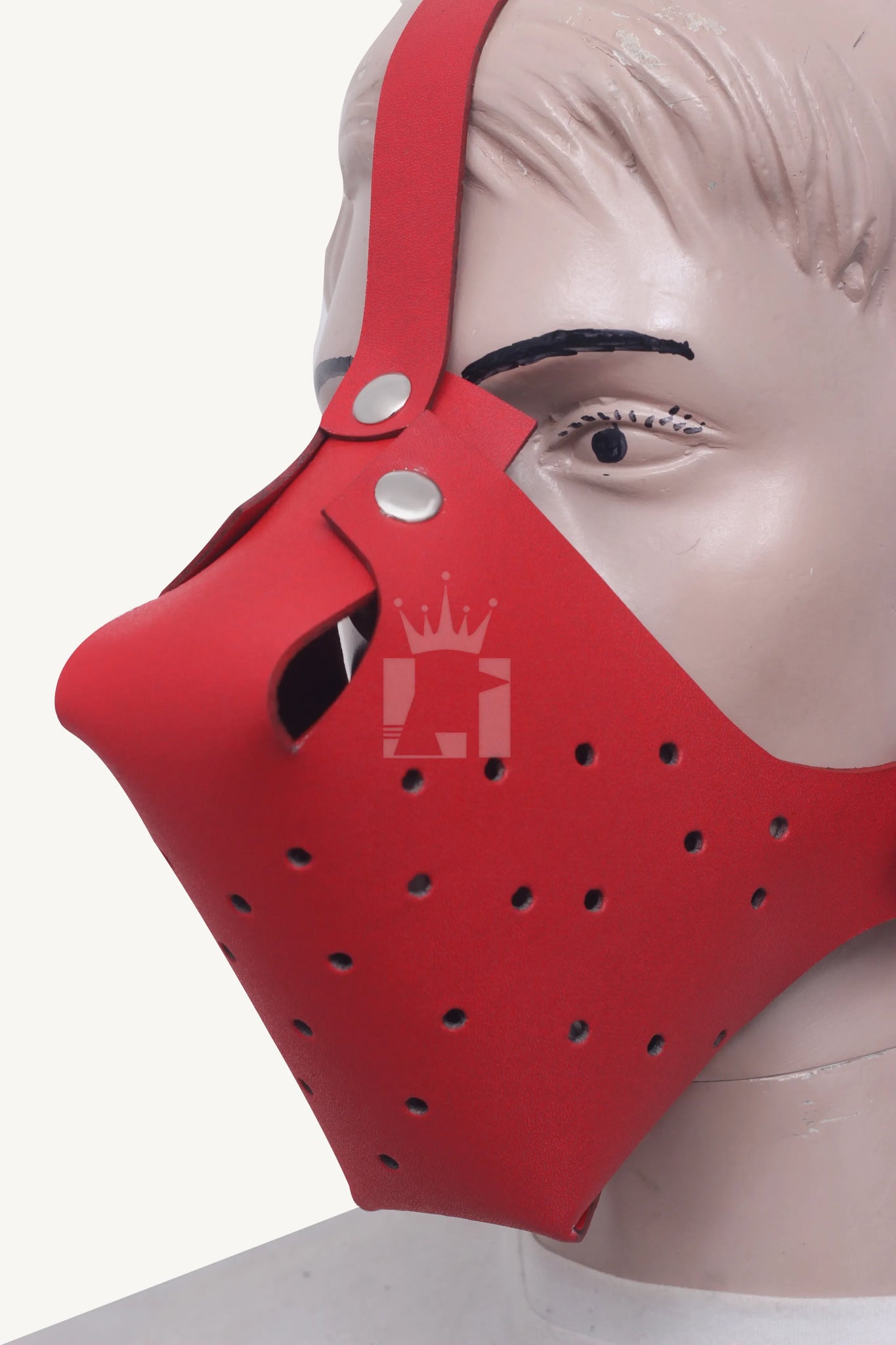 Close-up angled view of mannequin wearing red leather bondage muzzle with perforated front and forehead strap.