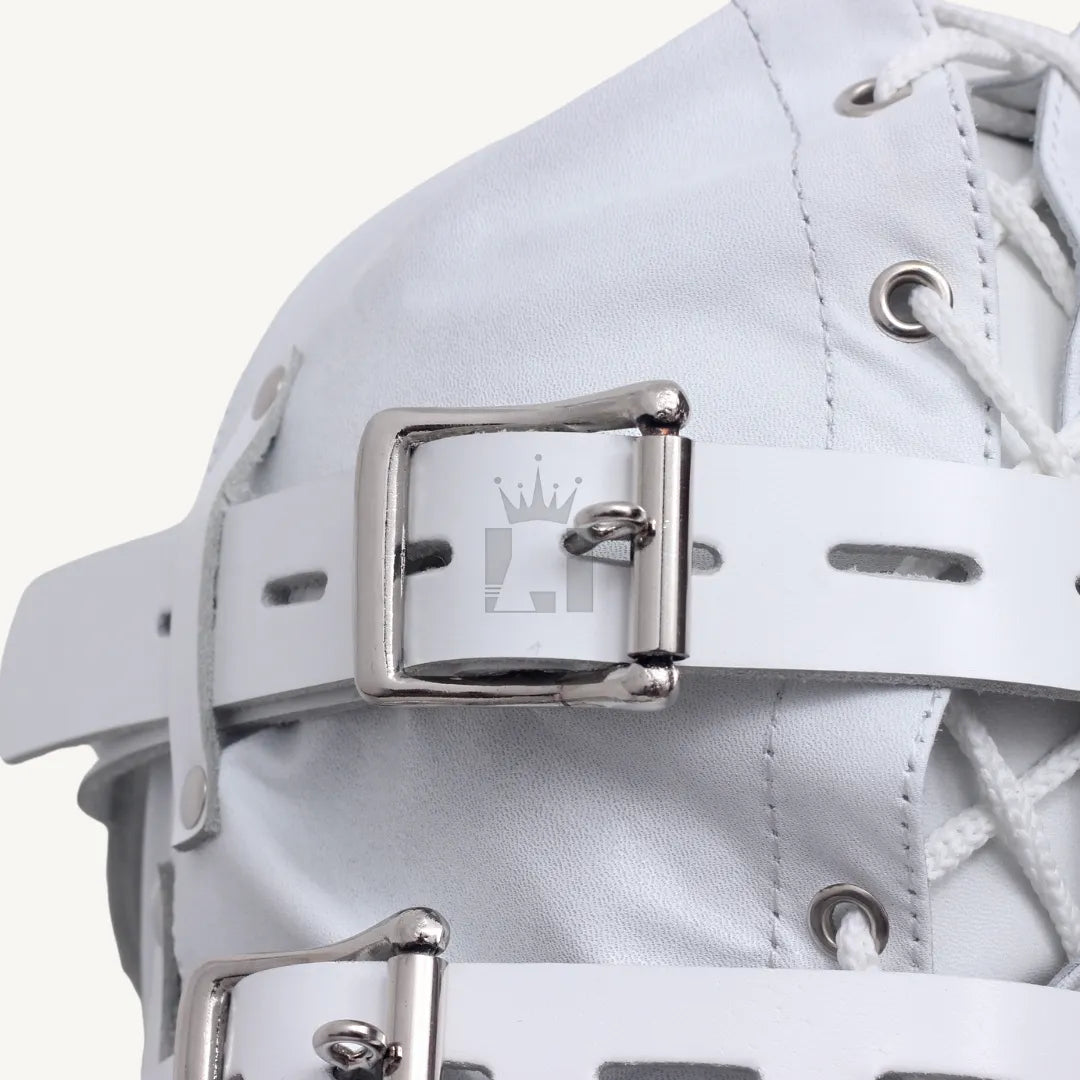 Close-up view of silver buckle fastening strap on white leather bondage hood.