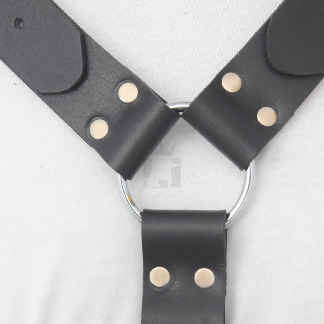 Detailed view of silver O-ring with leather straps connected by rivets on a black leather harness.
