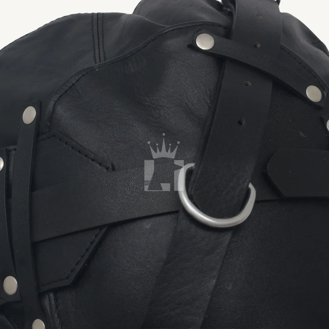 Detailed close-up of black leather bondage hood showing silver rivets and D-ring on strap.