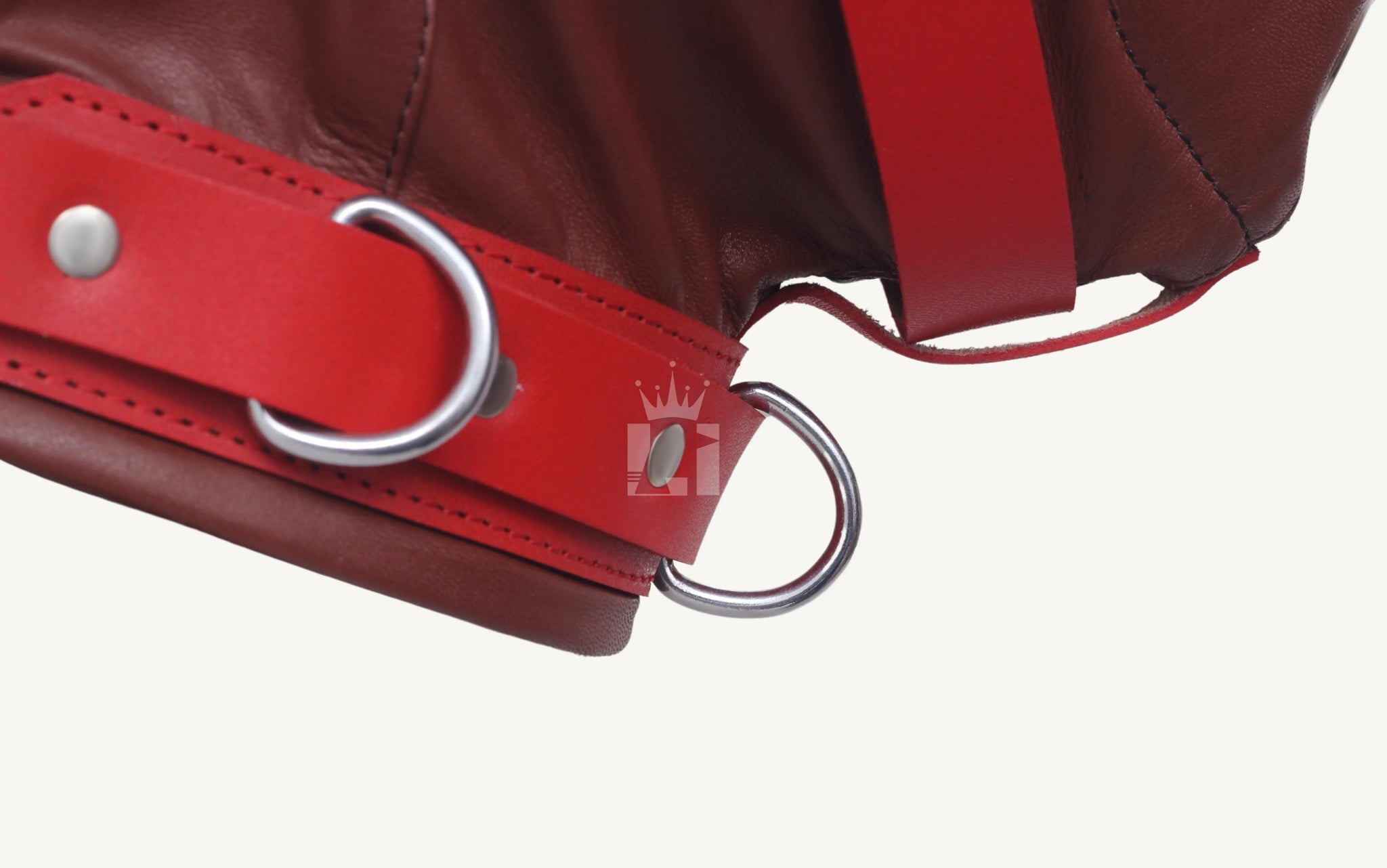 Close-up of red strap with silver D-rings and rivets on the bondage hood.