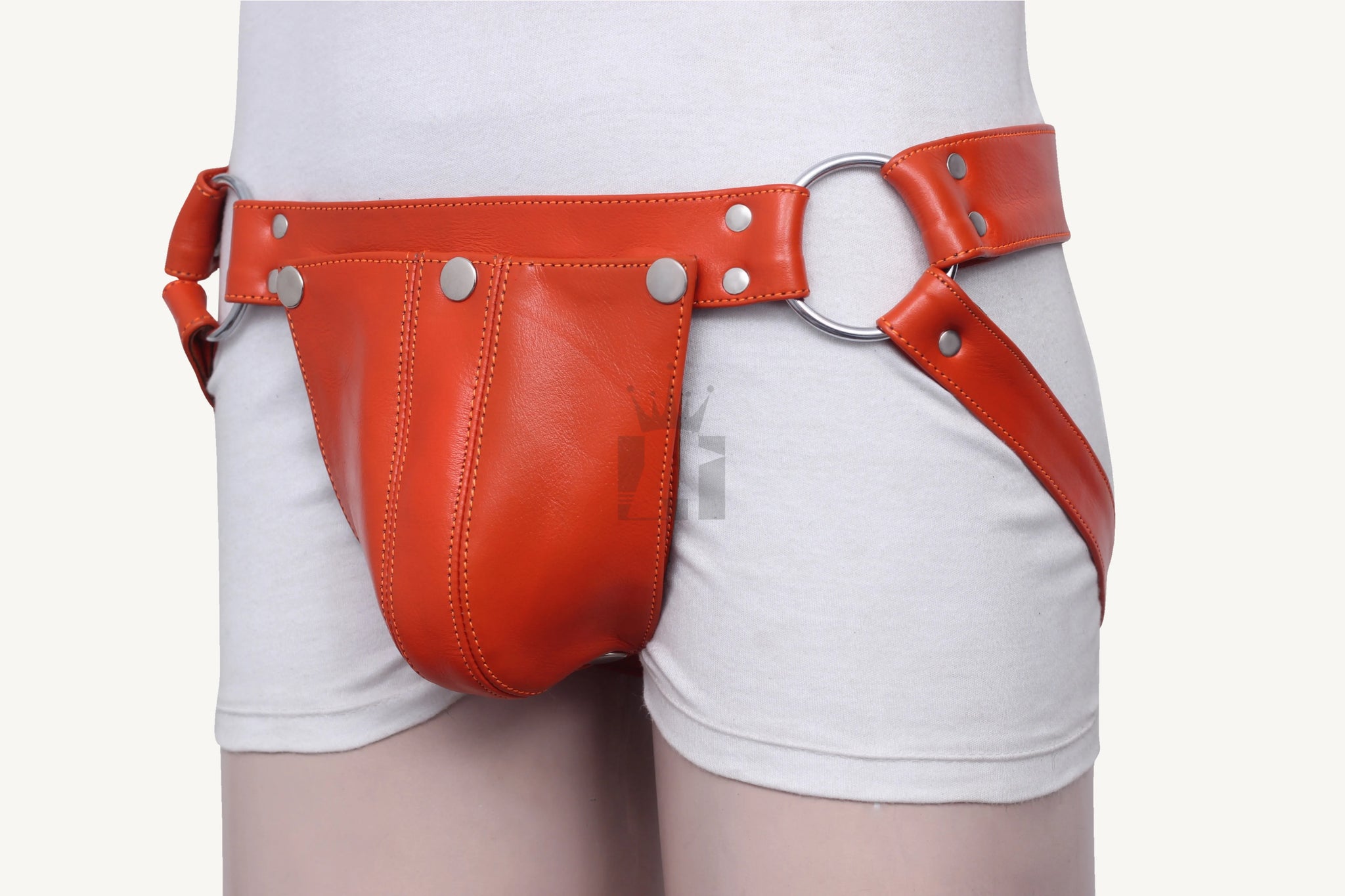 Model wearing leather jockstrap featuring wide waistband, codpiece, and metal O-rings.