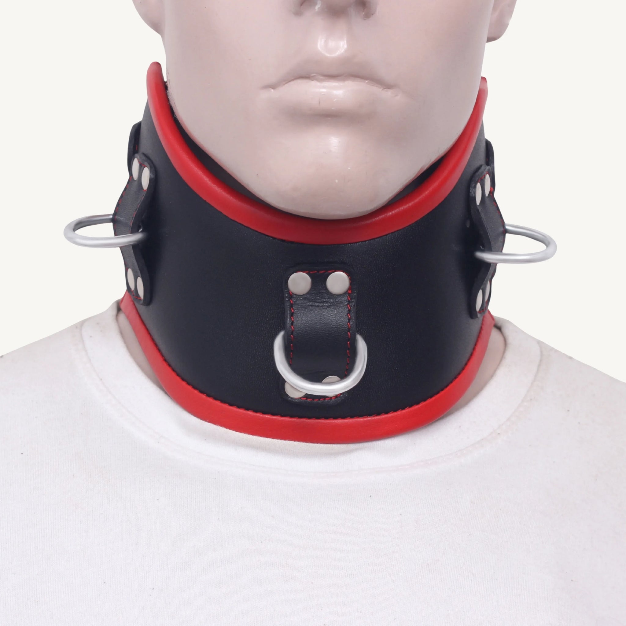 Close-up front view of a black and red leather bondage neck collar with D-rings and padded edges.