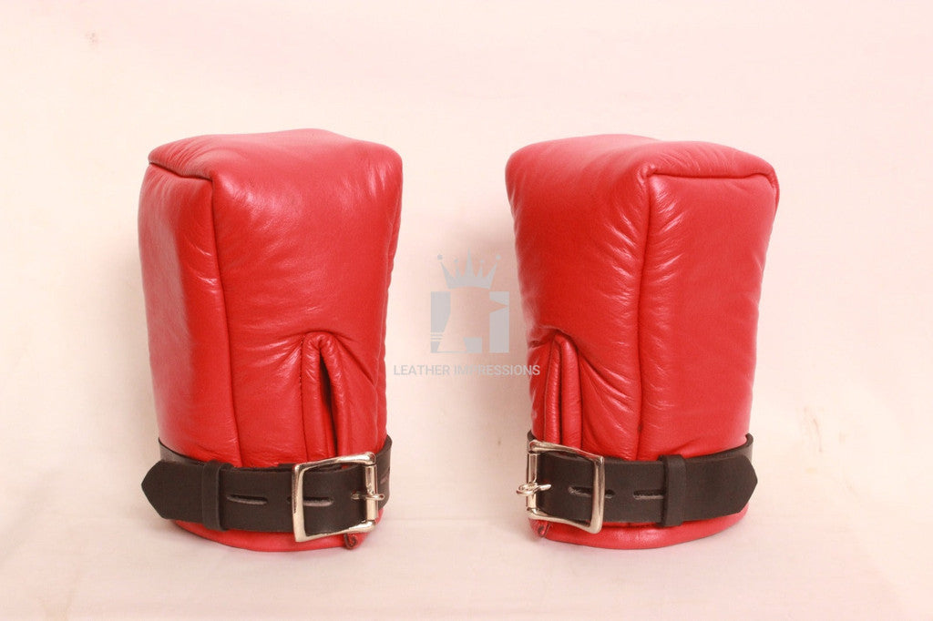 Front view of a pair of red padded leather bondage mittens with black leather straps on a plain white background.