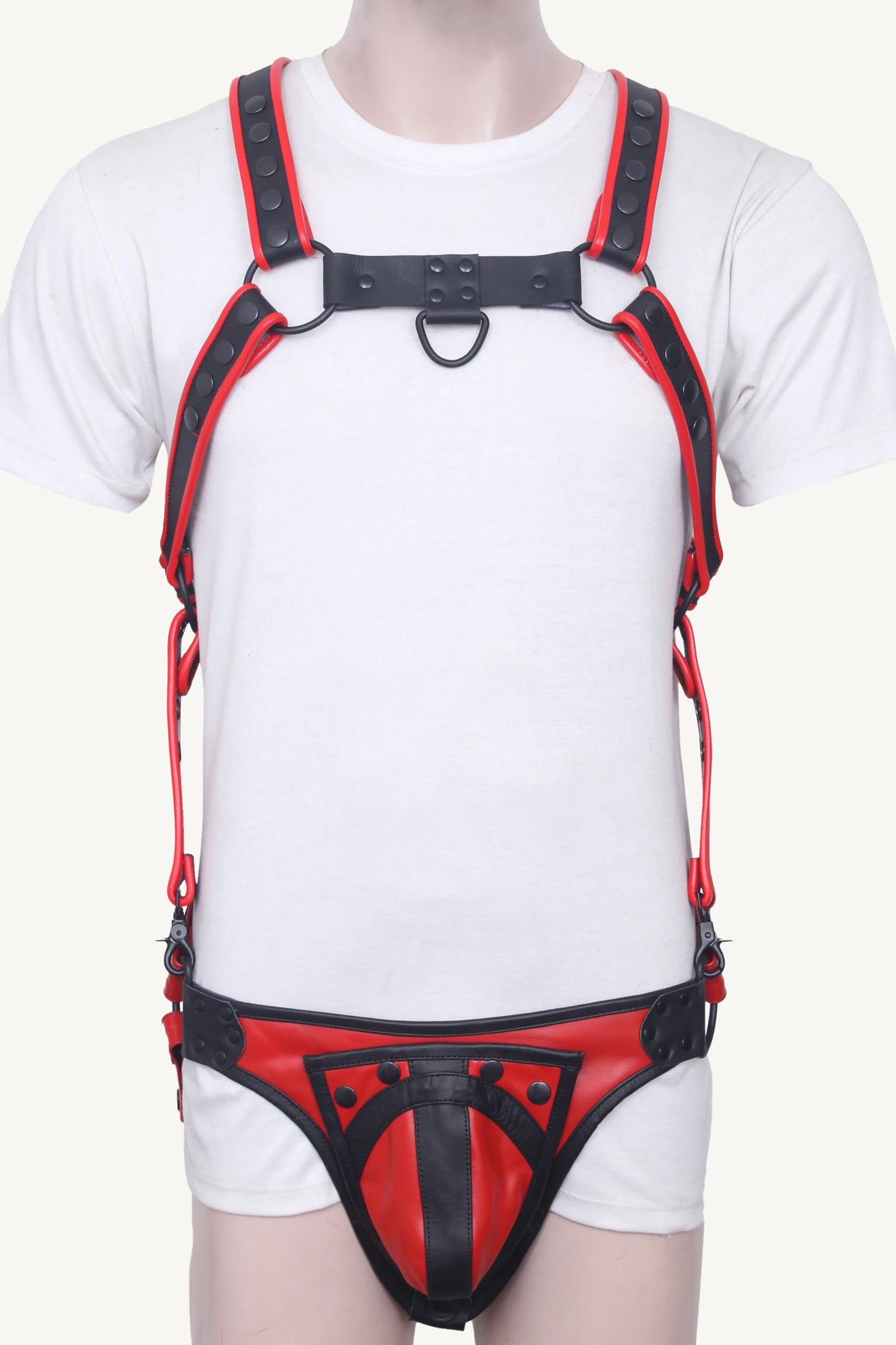 Model wearing full chest and waist harness in red and black leather with codpiece front pouch.