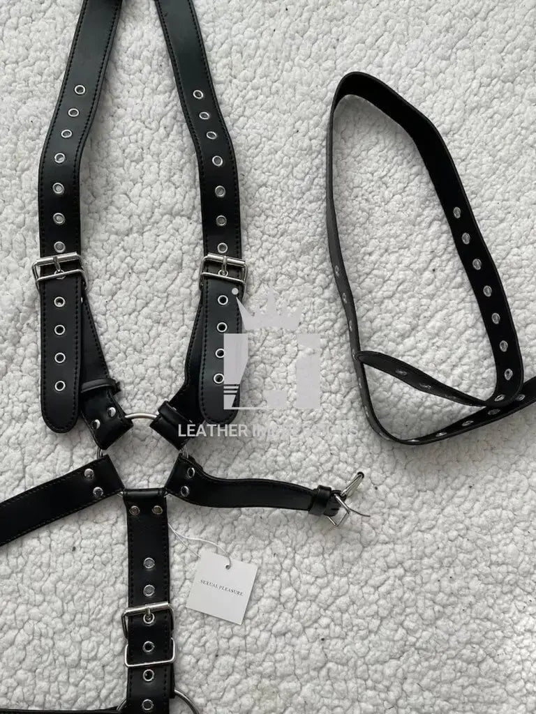 Front angle view of a black Men's Leather Harness with Cock Ring with strap on a white leather texture surface 