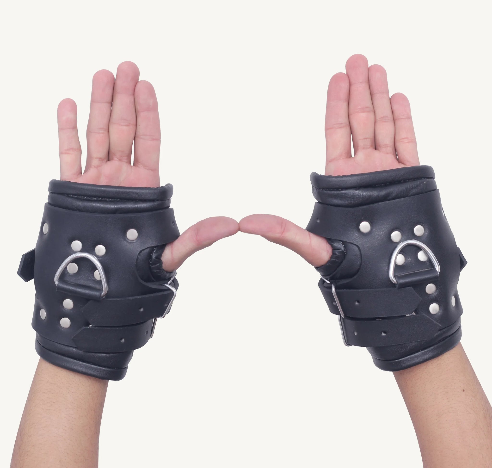 Palm-facing view of black suspension cuffs with padded leather design and metal D-rings for restraint.