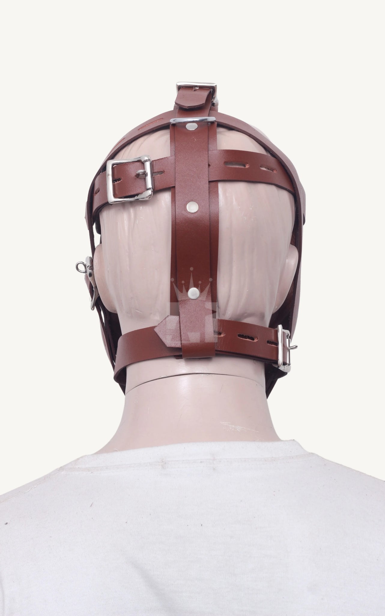 Back view of brown leather bondage muzzle with crossing straps and metal buckles on mannequin head.