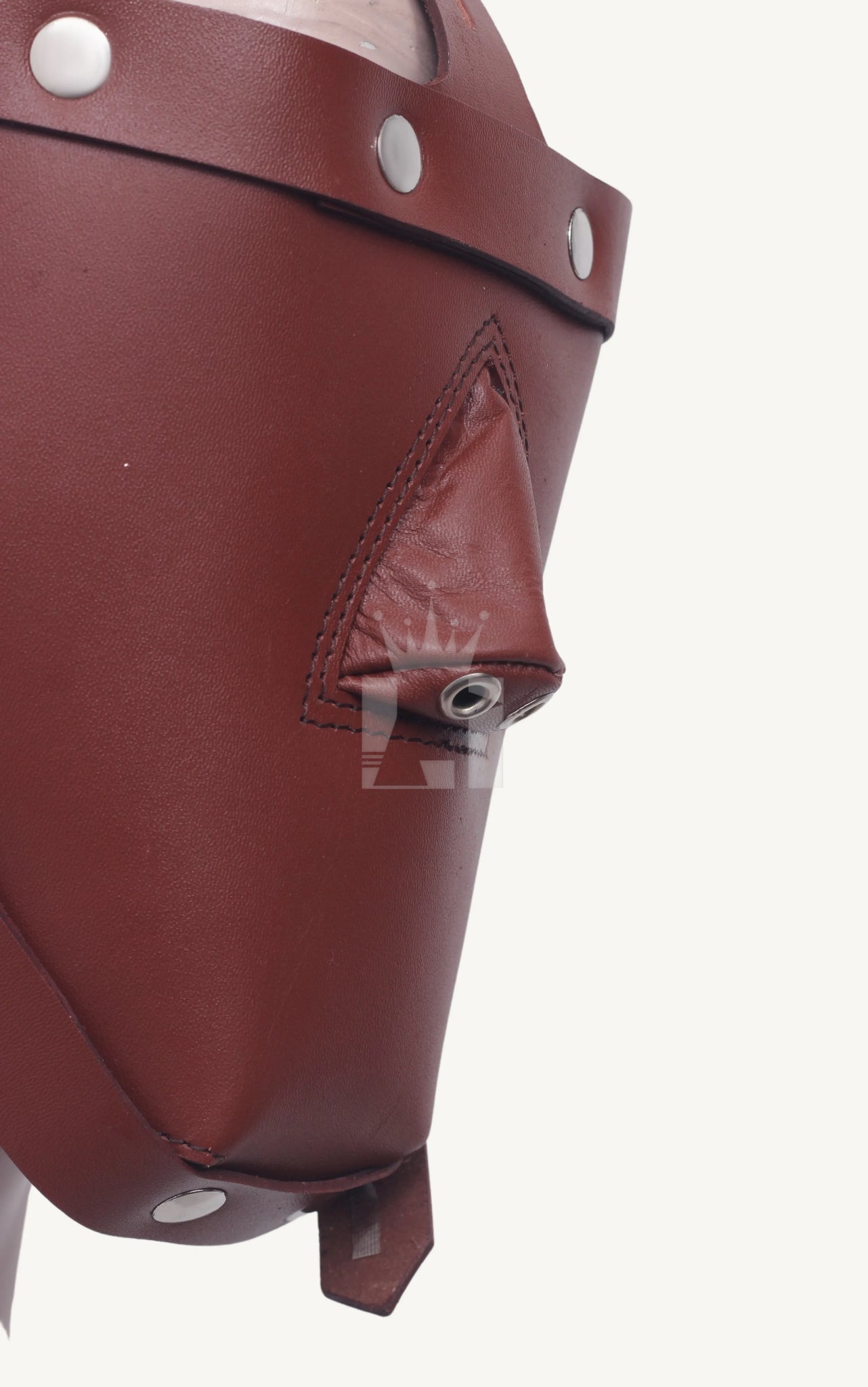 Close-up side angle of a brown leather bondage muzzle showing stitched nose covering and metal eyelets.