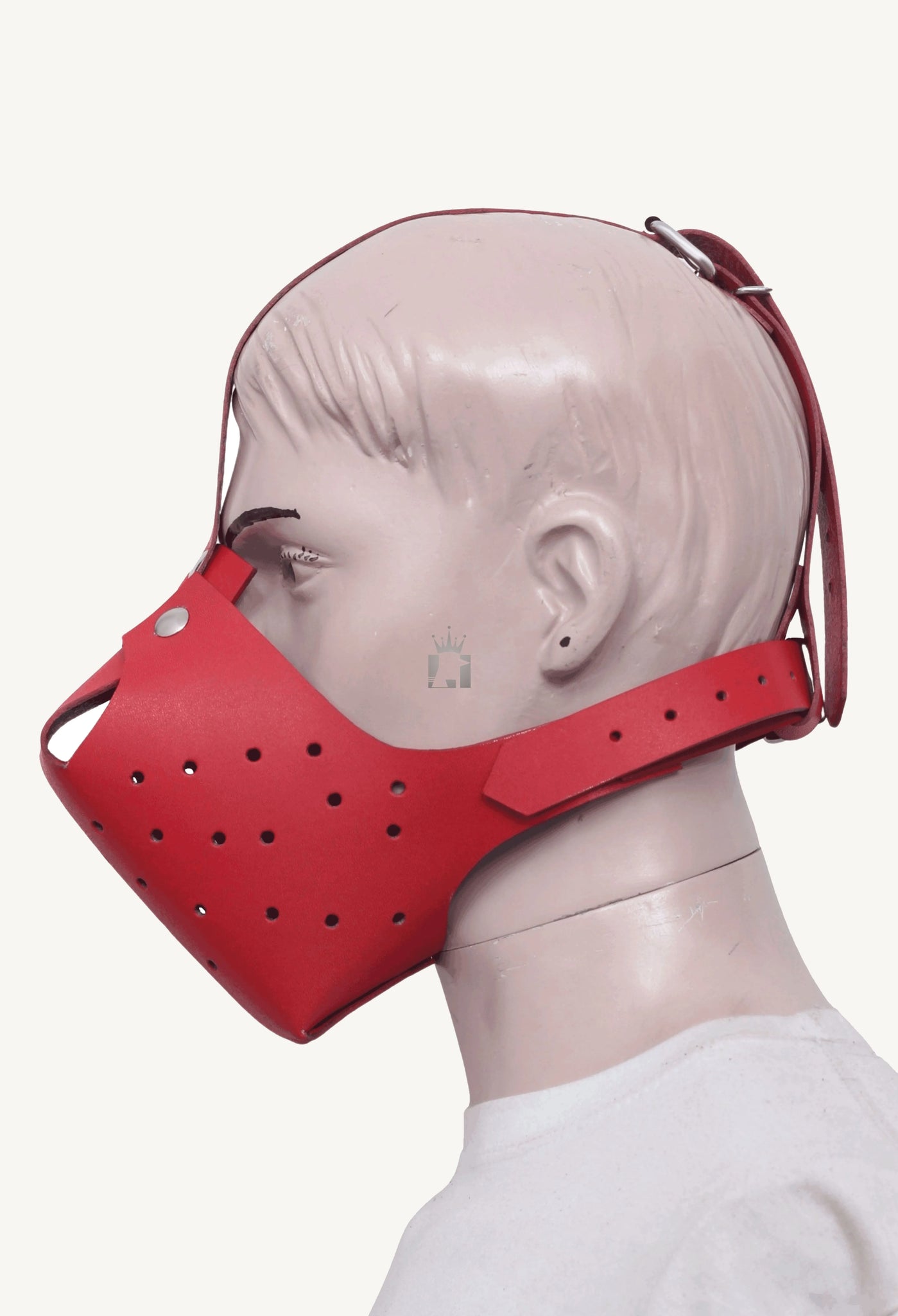 Side profile of a mannequin wearing the red leather pet play muzzle. This view shows how the mask covers the jaw and the adjustable strap that fastens around the back of the head.