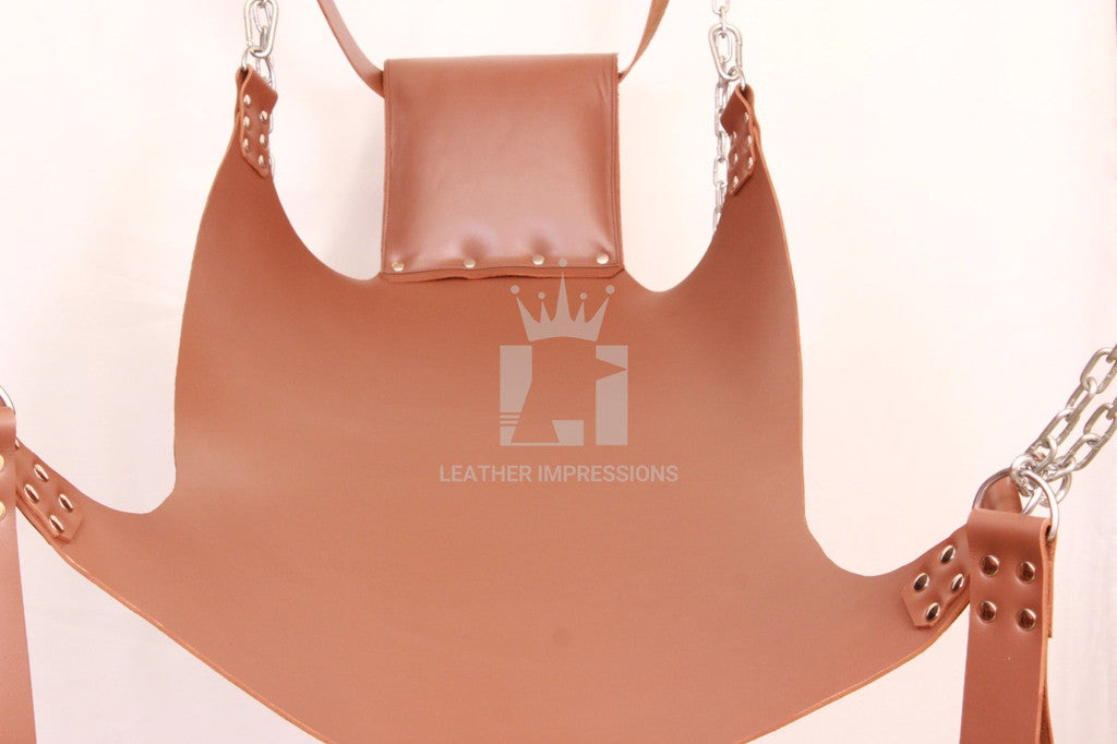 front angle view of brown leather sex swing with pillow, d-ring and nickel-plated reverts, leg loops on a white background in landscape format