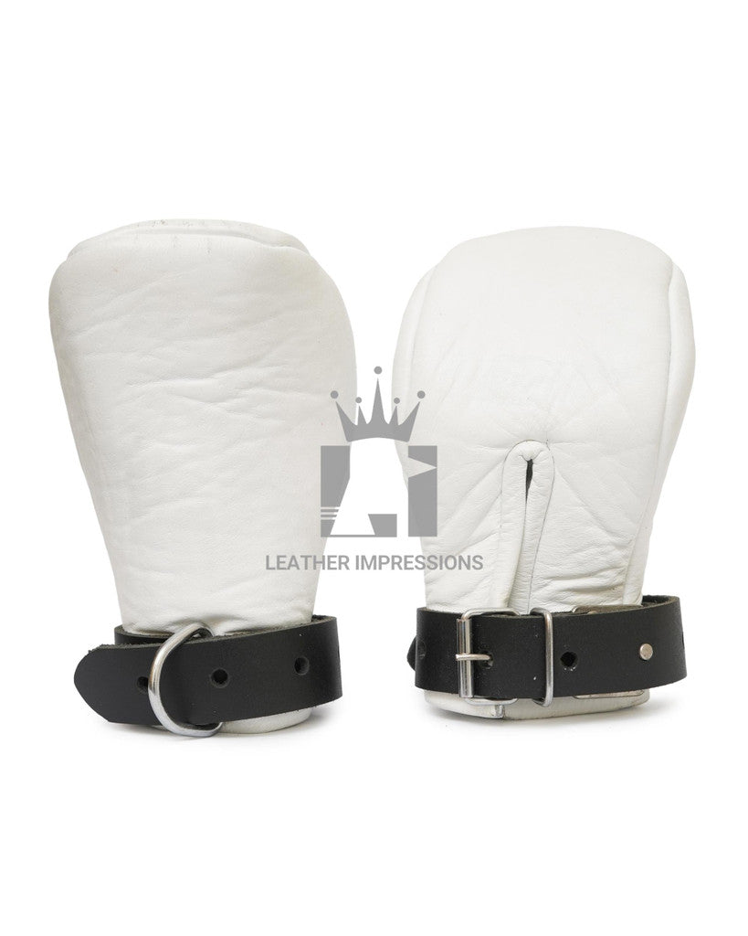 Front angle view of a pair of white padded leather bondage mittens with black leather straps. One glove leans against the other on a plain white background.