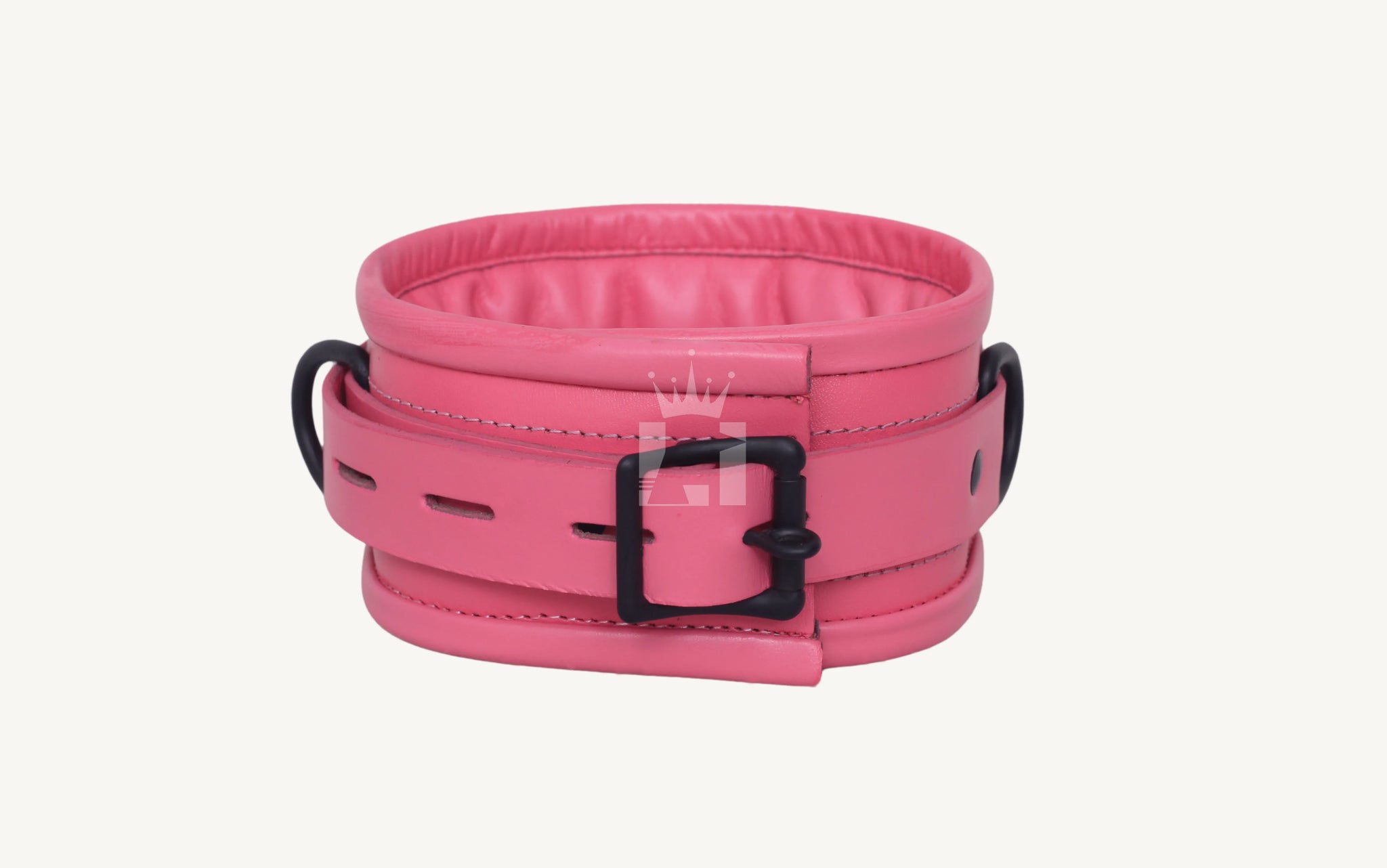 Close-up angled view of pink leather BDSM cuff featuring padded interiors, black metal buckles, and D-rings, designed for comfortable restraint in BDSM play.