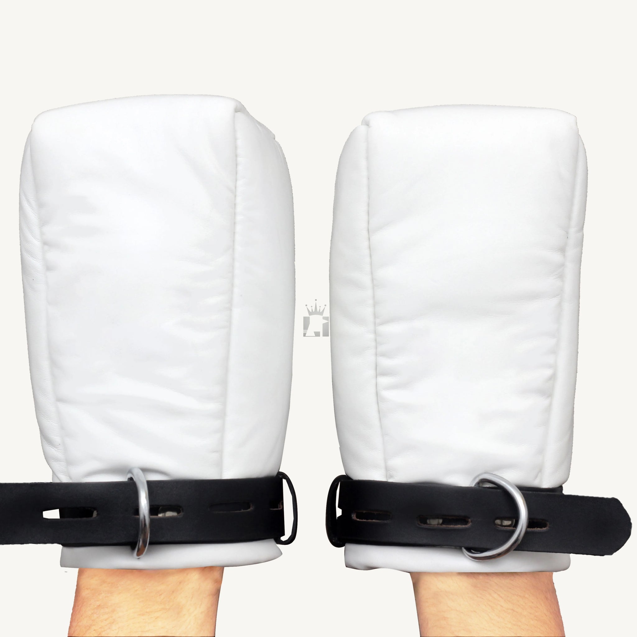 Front view of a pair of white premium leather bondage mittens with a black strap, held by hands against a neutral background.
